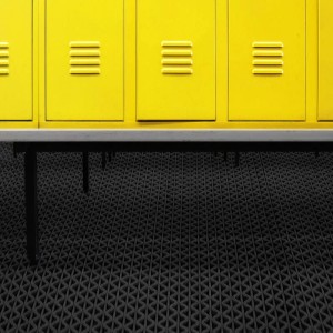 Schwarze KARAT Hygienematte 120x800 cm für Barfußzonen vor gelben Spinden.