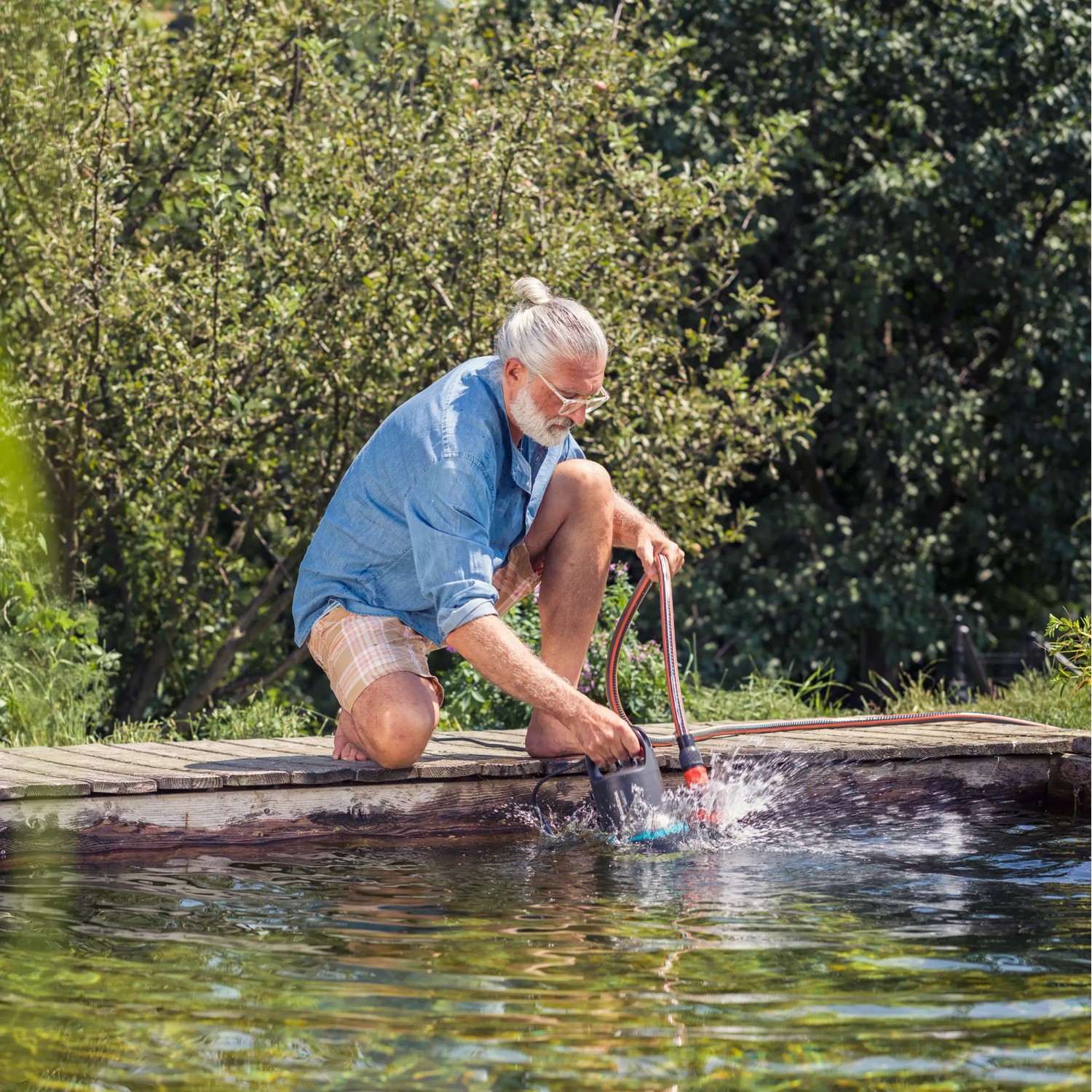 Mann nutzt Gardena Schmutzwasser-Tauchpumpe 9000 zum Abpumpen eines Teichs.