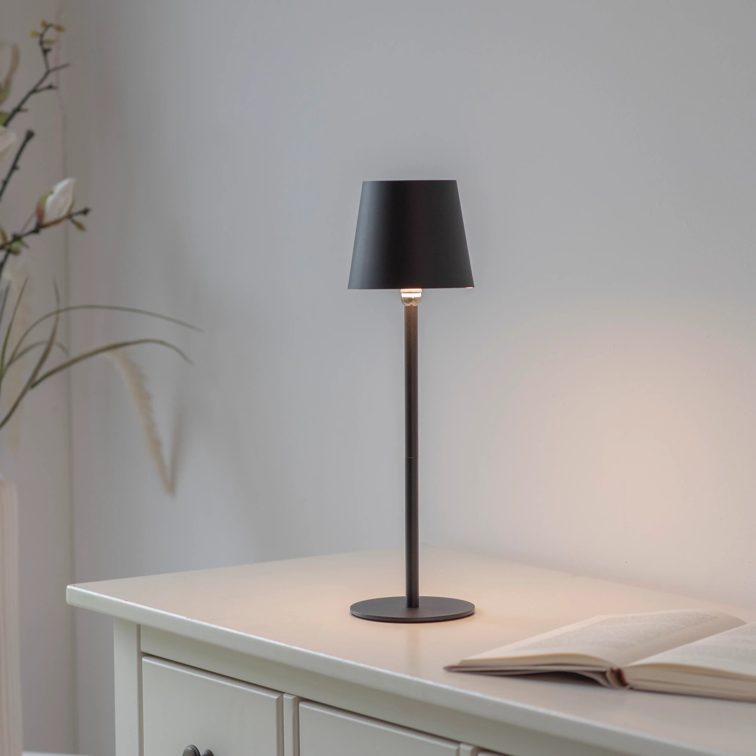Schwarze Just Light Akku-LED-Tischleuchte Boteria, Ø 11 cm, 37 cm hoch, auf Tisch.