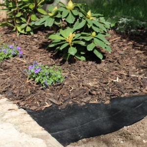 Schwarzes Windhager Unkrautvlies 50 g/m² im Gartenbeet unter Rindenmulch.