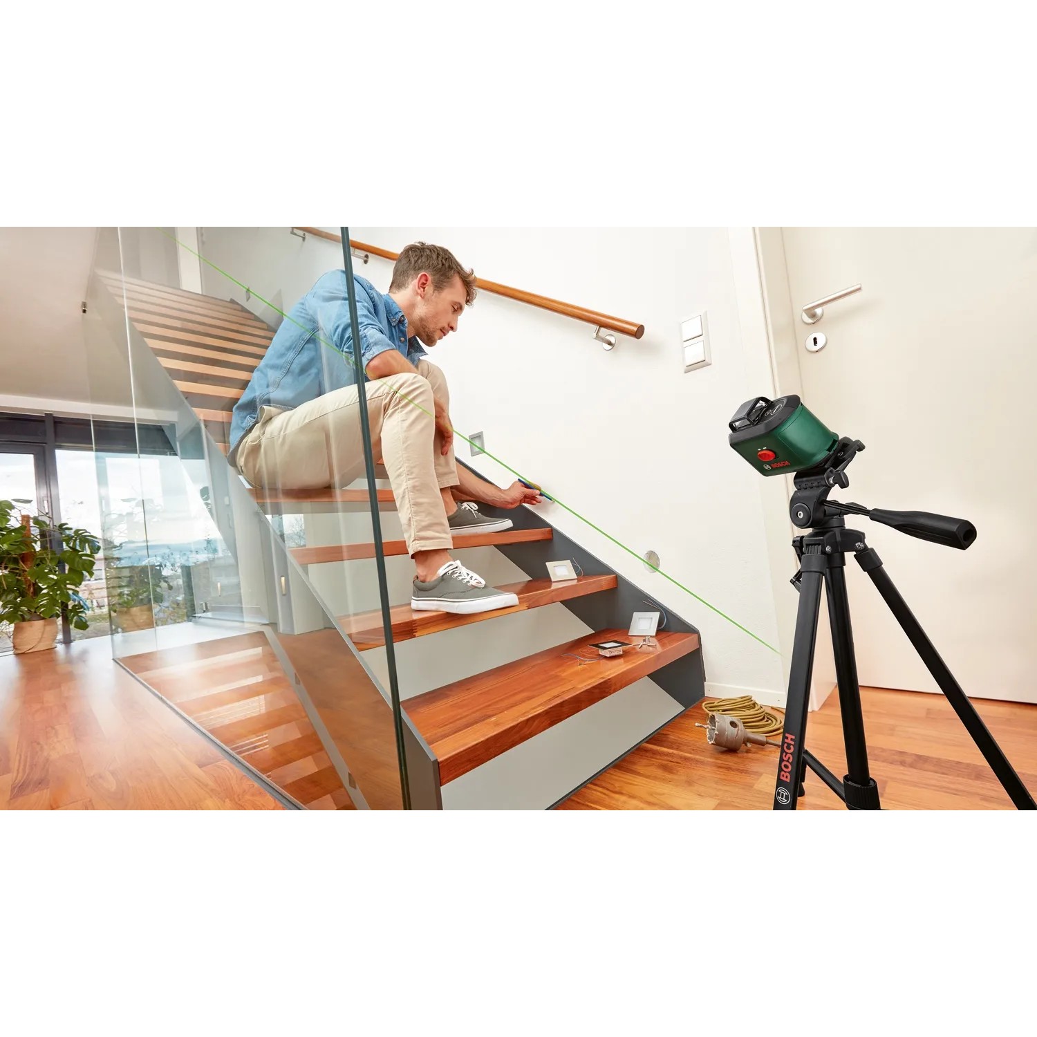 Bosch UniversalLevel 360 Kreuzlinienlaser im Einsatz auf Stativ, projiziert grüne Laserlinie an Treppe.