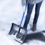 Person räumt Schnee mit blauer Westfalia Teleskop-Schneeschaufel aus Stahl und Kunststoff auf Asphalt.