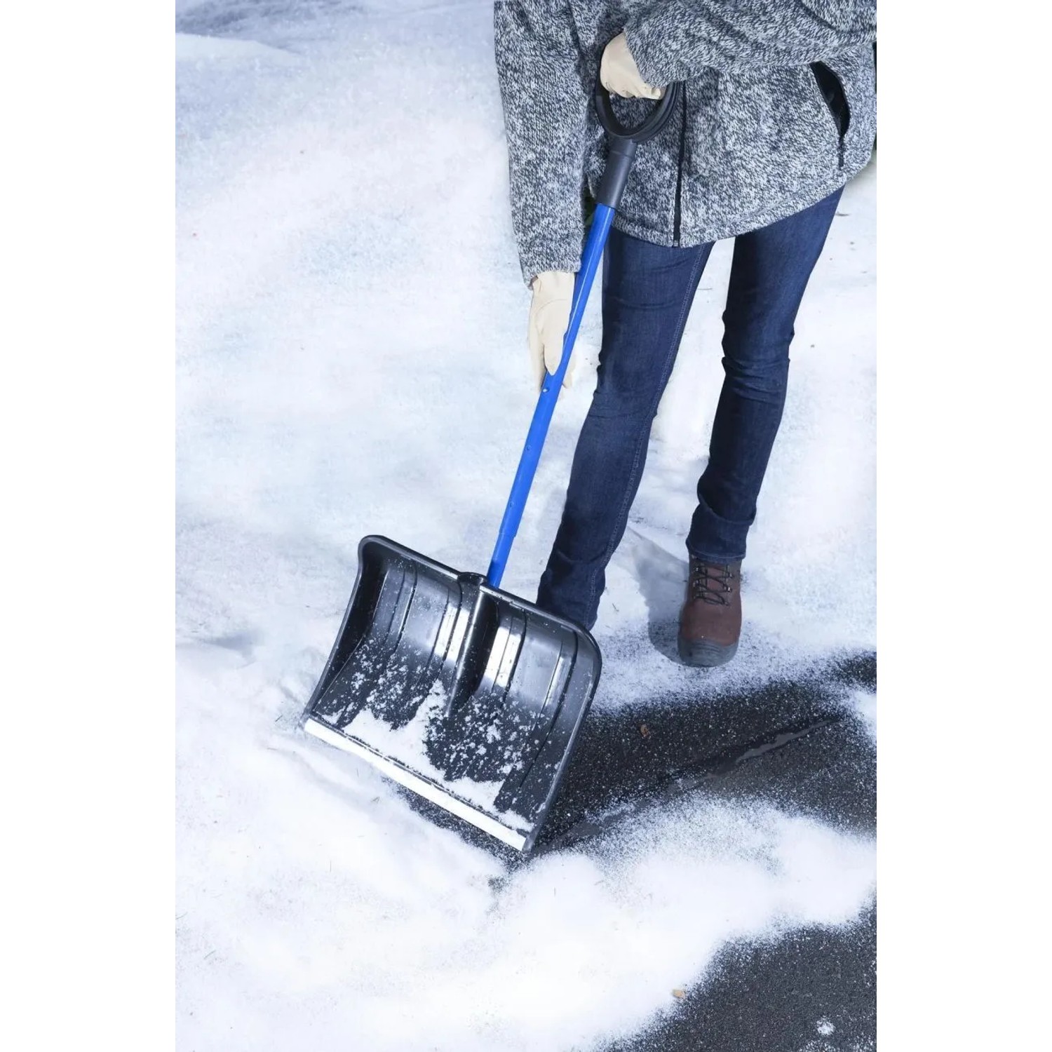 Person räumt Schnee mit blauer Westfalia Teleskop-Schneeschaufel aus Stahl und Kunststoff auf Asphalt.