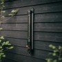 Fiskars Oszillierender Regner X-Series S-L, schwarz-orange, an dunkler Holzwand montiert.