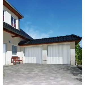 Hörmann Schwingtore Pearl, verkehrsweiß, an Doppelgarage mit Pflastersteinen und Bank vor dem Haus.