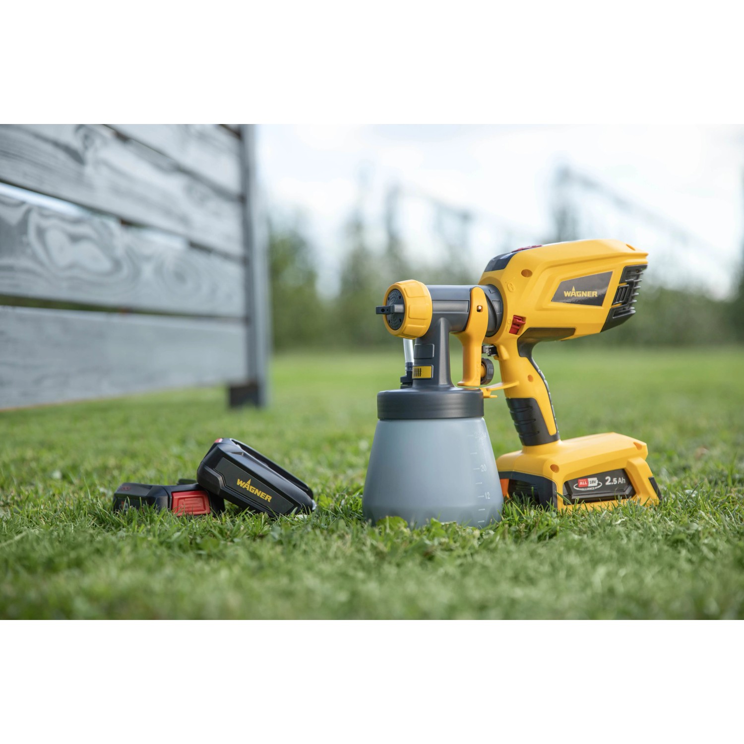Wagner Akku-Farbsprühsystem W 600 FLEXiO 18V mit Sprühaufsätzen auf Rasen.