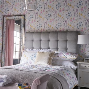 Schlafzimmer mit Laura Ashley Vliestapete Wild Meadow mit Blumenmuster in Gelb, Rosa und Blau.