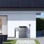 Anker Solix Solarbank 4 E5000 Pro Solarspeicher am Haus. Graue Einheit mit PV-Modulen auf Dach und Rasen. Balkonkraftwerk.