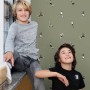 Olivgrüne Vliestapete mit Fußballspielern im Kinderzimmer, zwei Jungen lächeln. Dekorative Tapete.