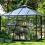 Juliana Gewächshaus Grand Oase 13, anthrazit, mit Personen, Pflanzen und Gartenzubehör.