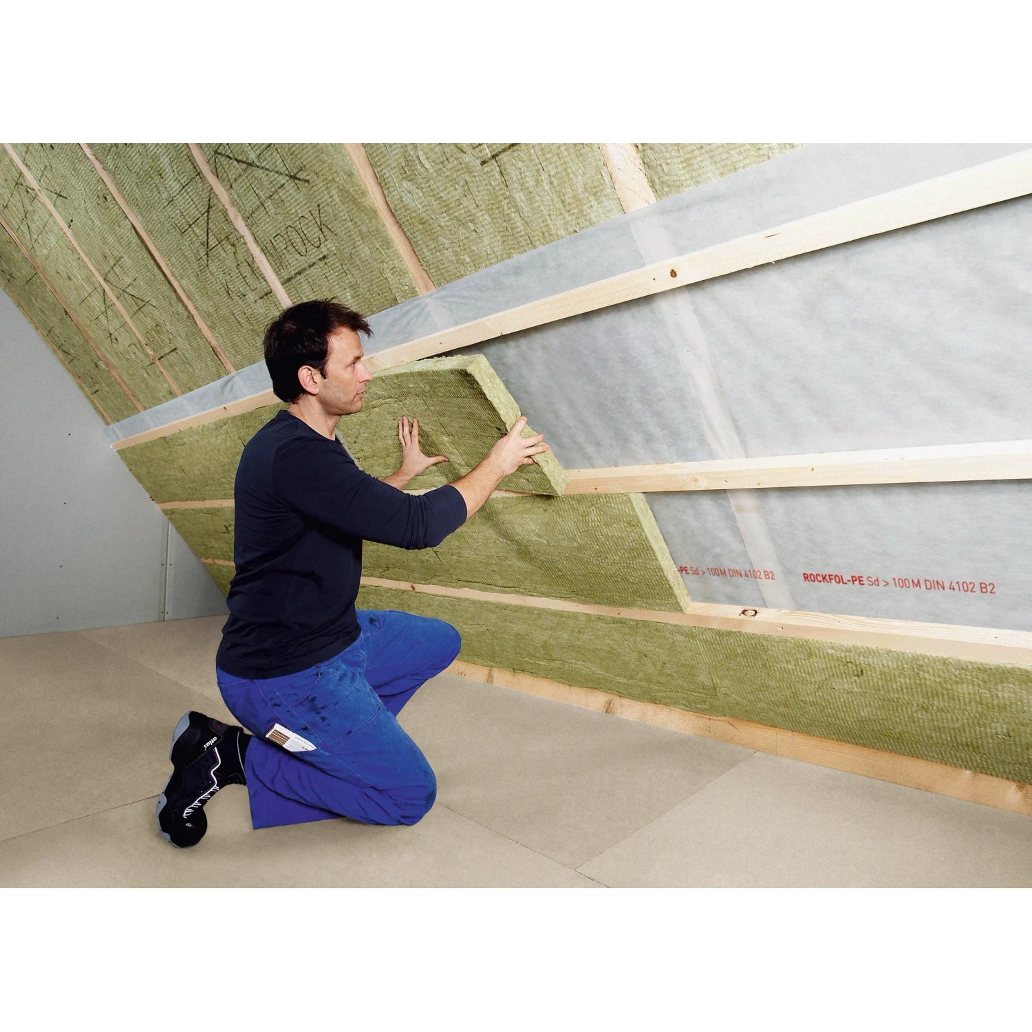 Mann verlegt Rockwool Formrock Untersparrendämmung (60mm) zwischen Holzsparren.
