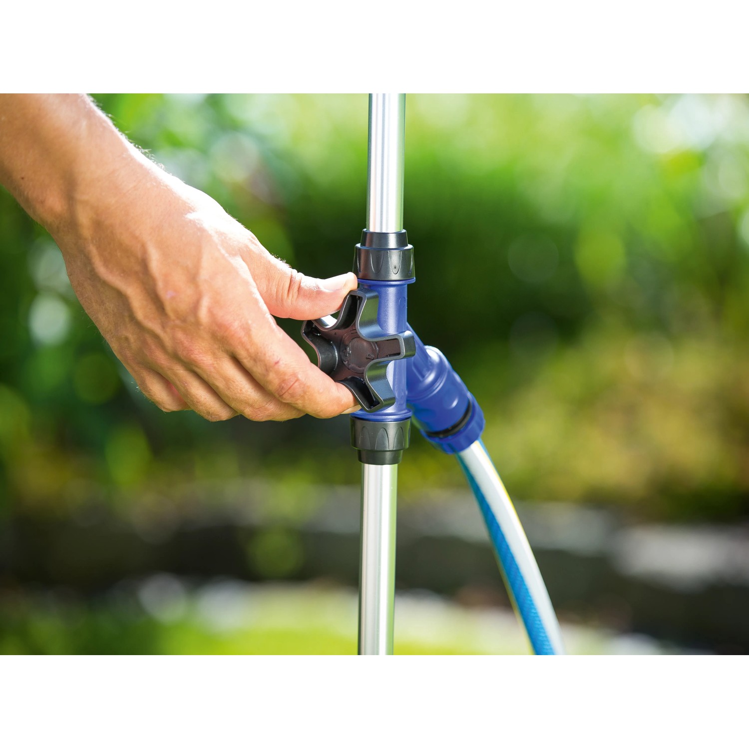Detailaufnahme: Hand bedient Regler der LUX Gartendusche. Wasserschlauchanschluss sichtbar.