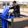 Westmann Mülltonnenverkleidung Planum für 2 Tonnen (240 l) in Holzoptik. Person wirft Müll ein.