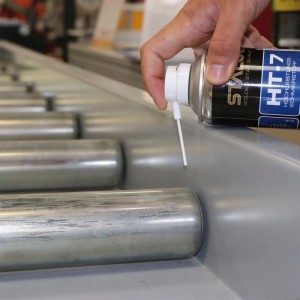 Hand sprüht Staloc HT-7 Hochleistungs-Schmierstoff auf Rollen einer Förderanlage. Spezial-Spray für bewegliche Teile.