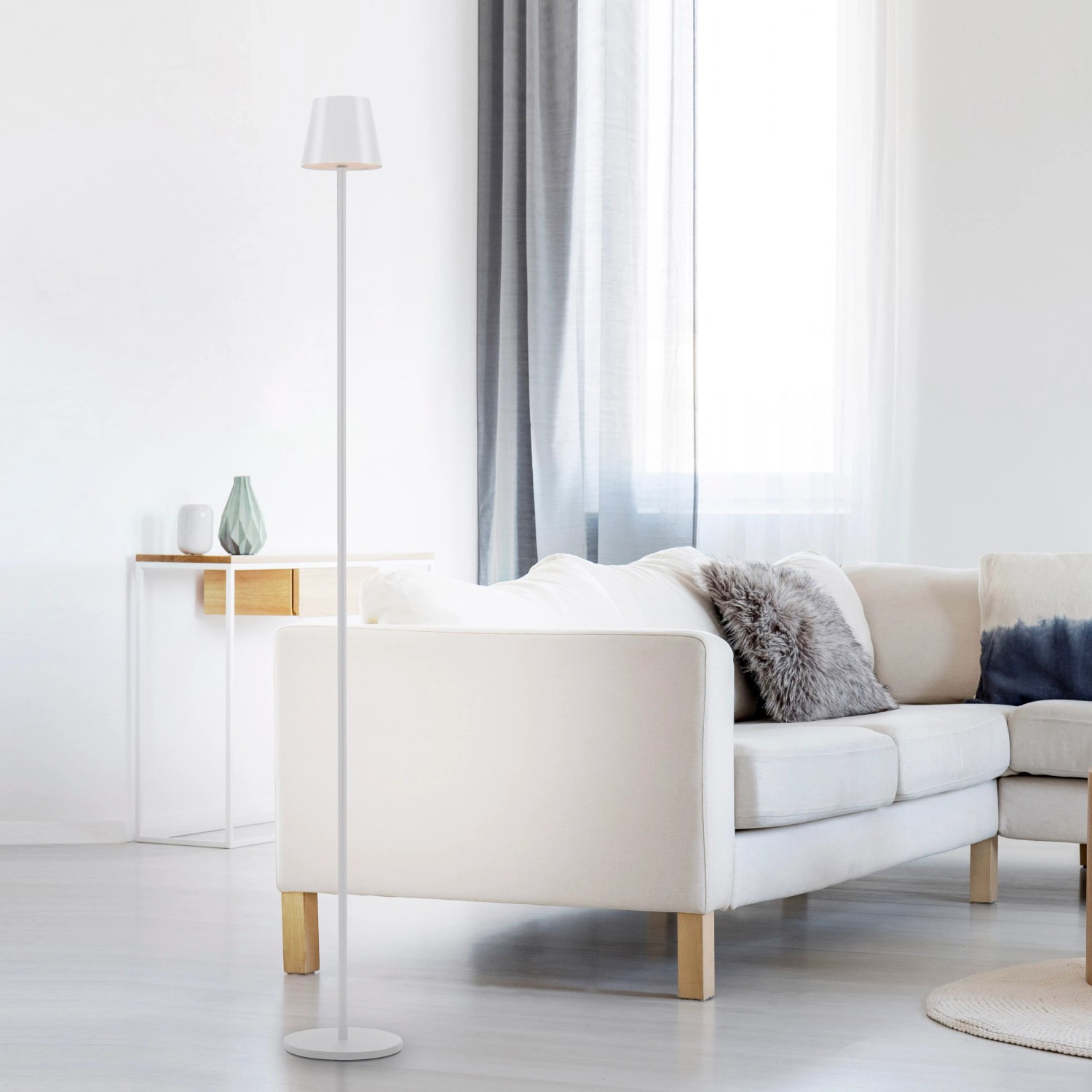 Weiße LED-Akku-Stehleuchte Euria (125 cm) im Wohnzimmer. Dekorative Außenleuchte mit warmweißem Licht.