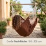 Brauner AMANKA Hängesessel aus Baumwolle. Eine Person entspannt auf einer Terrasse mit Pflanzen. Ideal für Garten & Outdoor.