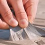 Hand drückt schwarzes HSS Dach Reparaturband auf raue Oberfläche. Wasserdichte Bauabdichtung für schnelle Reparaturen.