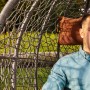 Grauer Home Deluxe Hängesessel Cielo Polyrattan mit Mann, Kissen und Regenschutz