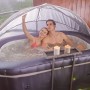 MSpa Urban Whirlpool Nest AirJet mit Paar und Rattan Beistelltisch unter Überdachung.