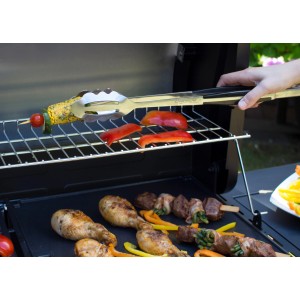 Campingaz Grillzange aus Edelstahl beim Grillen von Gemüse und Hähnchen.