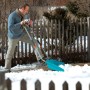 Gardena Schneewanne 70 cm im Einsatz: Mann schiebt Schnee mit dem Schneeschieber vor einem Haus.
