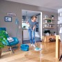 Frau wischt Holzboden mit Leifheit Clean Twist Disc Mop Ergo Reinigungsgerät und Eimer.