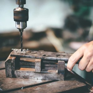 Metallbohrer bohrt in Werkstück, eingespannt in Schraubstock. KLASEBO Spiralbohrer Zubehör.