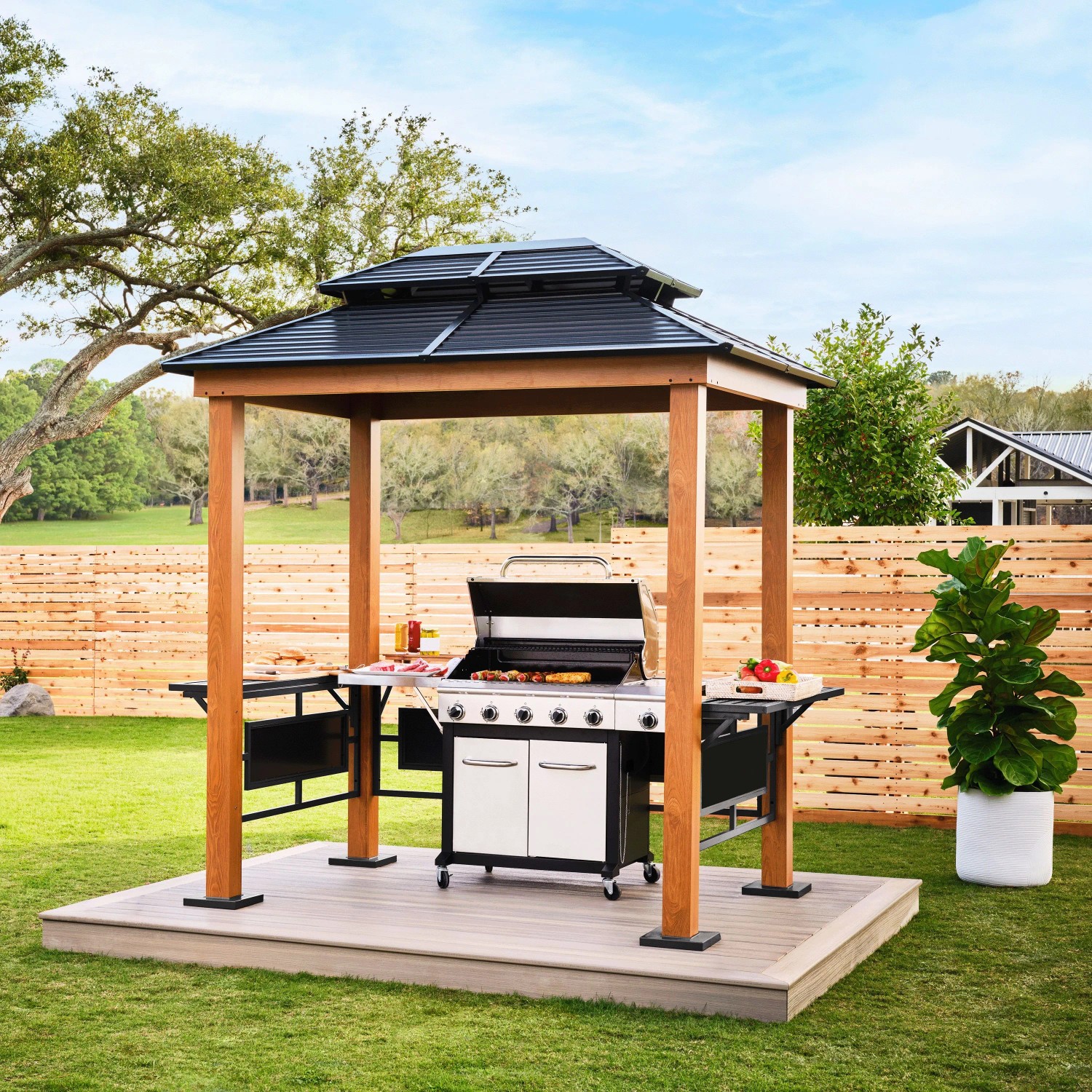SOJAG Grillpavillon Maui in Holzoptik mit schwarzem Stahldach, Grill und Seitenablagen im Garten. Terrassenüberdachung.